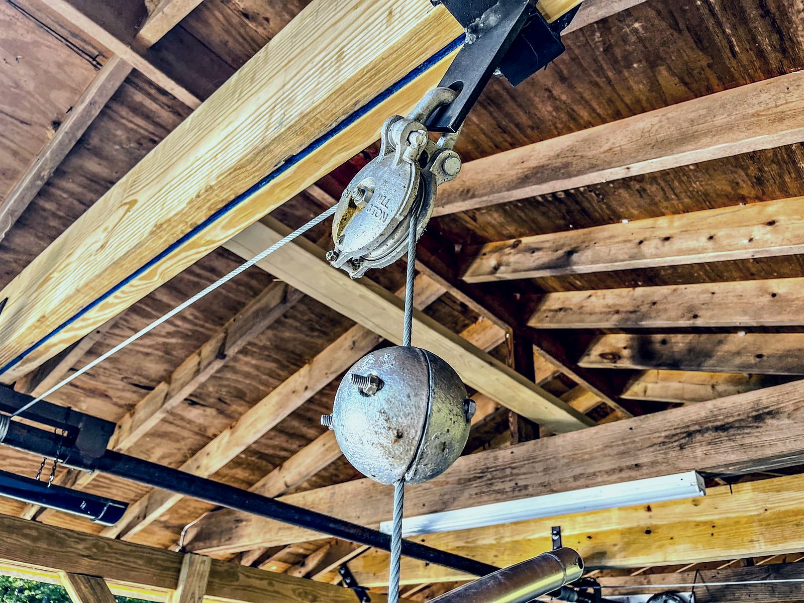 Boat lift cable, pulley and winch assembly under a boathouse roof